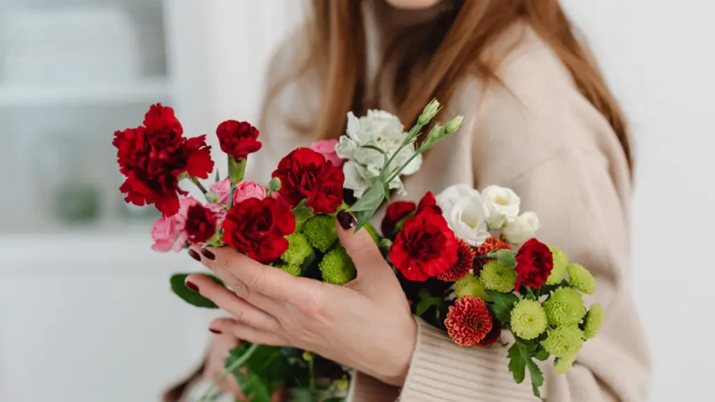 Femme tenant un bouquet de fleurs rouges et blanches (idée cadeau Saint-Valentin)